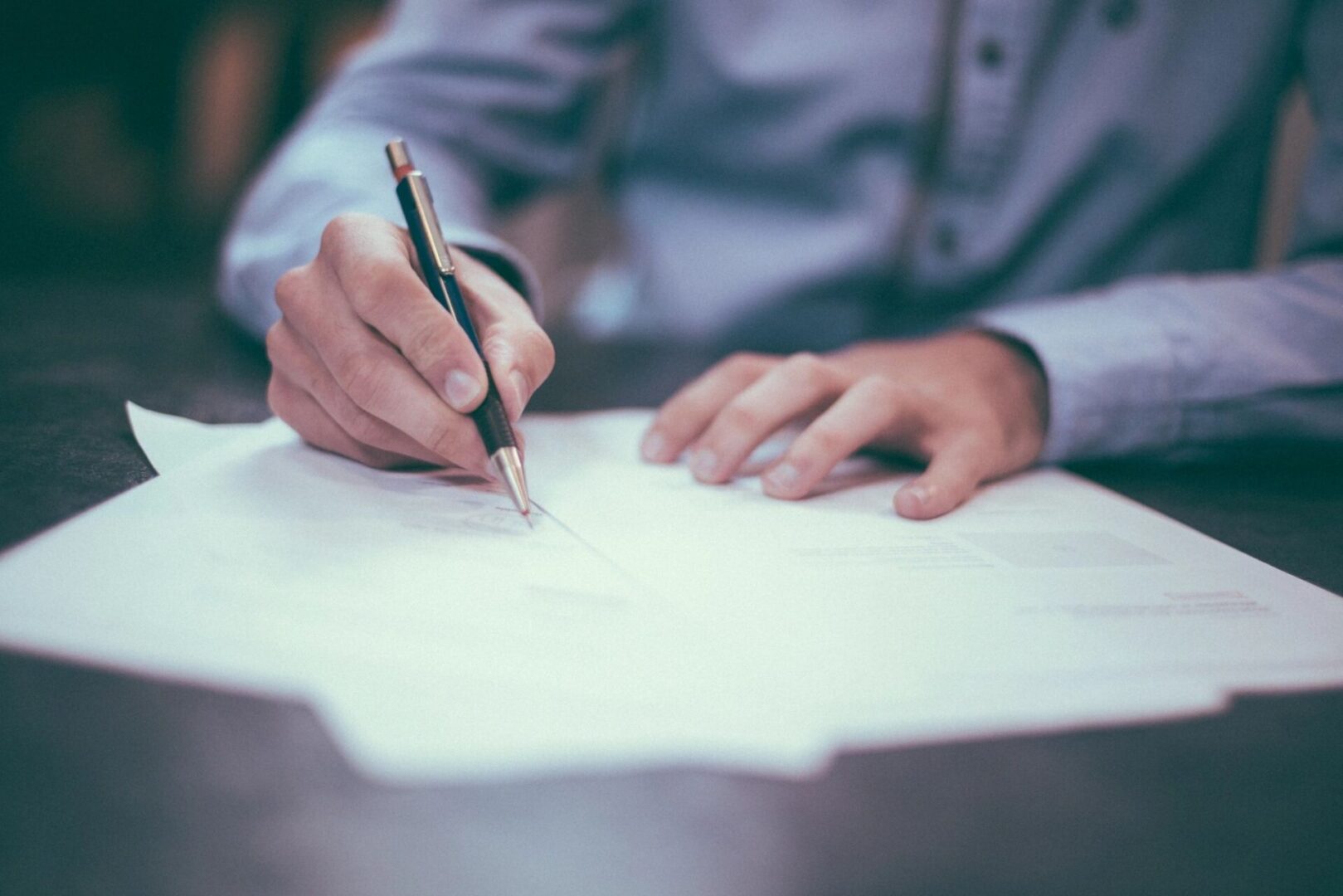 A person writing on paper with a pen.